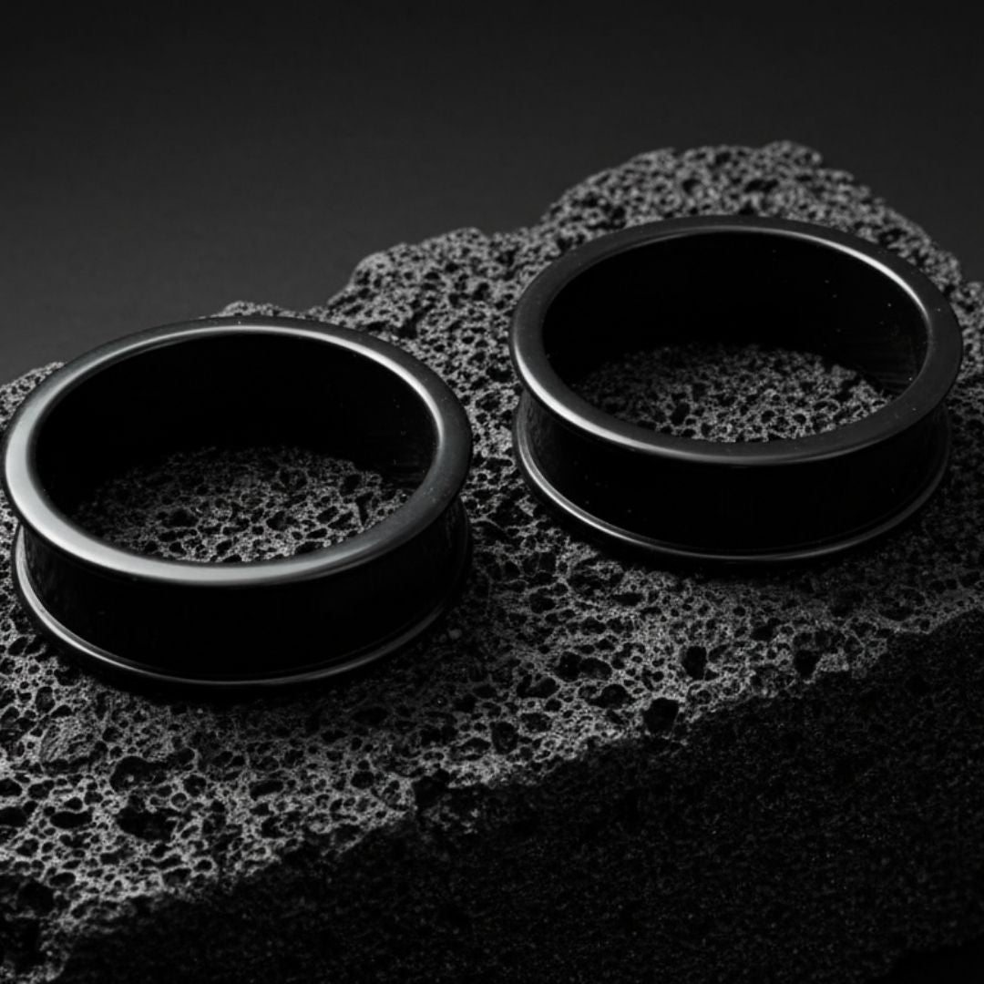 Pair of black thin-flare silicone tunnels (gauges) displayed against a dark background, showing the soft material texture.