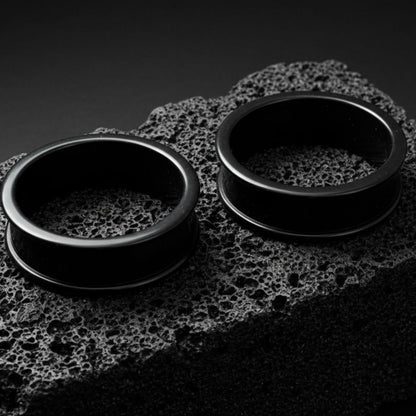 Pair of black thin-flare silicone tunnels (gauges) displayed against a dark background, showing the soft material texture.