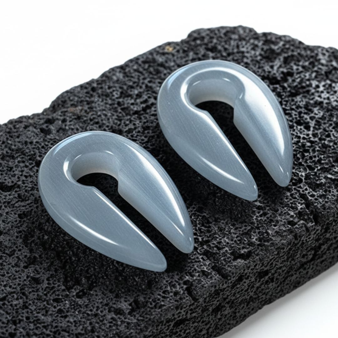 Close-up of Silver Dragon Eye Stone Hangers (6mm-10mm) on a rock against a white background.