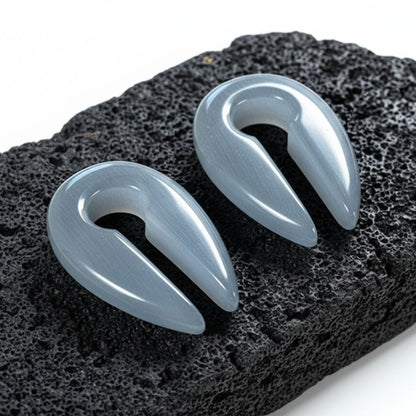 Close-up of Silver Dragon Eye Stone Hangers (6mm-10mm) on a rock against a white background.