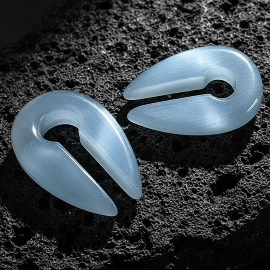 A pair of Silver Dragon Eye Stone Hangers on dark volcanic rock with dramatic lighting.