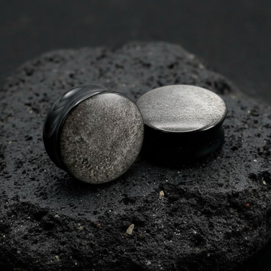 Pair of deep black Silver Obsidian stone plugs, polished, reflecting a subtle silver flash. Gauges displayed on a dark background.