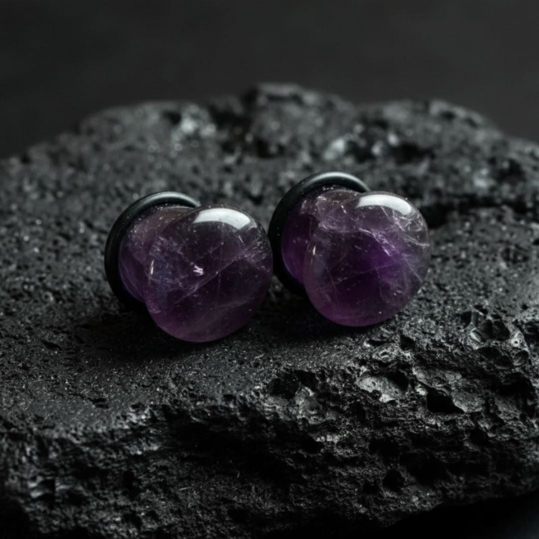 Close-up of deep purple Amethyst stone single flare plugs (gauges) on a white background. Natural alt jewelry for stretched piercings.