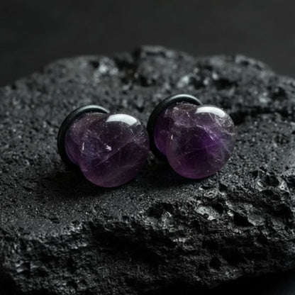 Close-up of deep purple Amethyst stone single flare plugs (gauges) on a white background. Natural alt jewelry for stretched piercings.