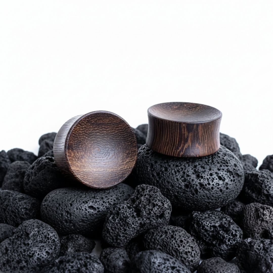 Pair of organic Snakewood plugs and tunnels, wood grain visible, displayed on a black background, available up to 25mm sizes.