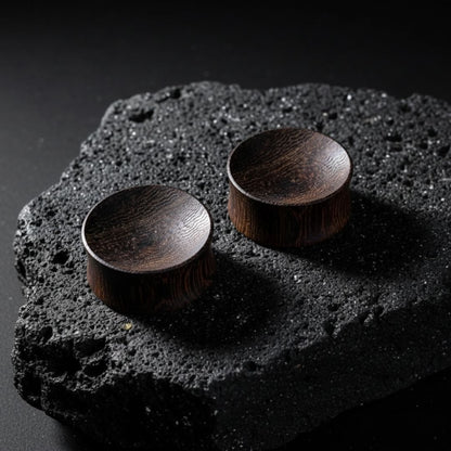 Pair of organic Snakewood plugs and tunnels, wood grain visible, displayed on a black background, available up to 25mm sizes.