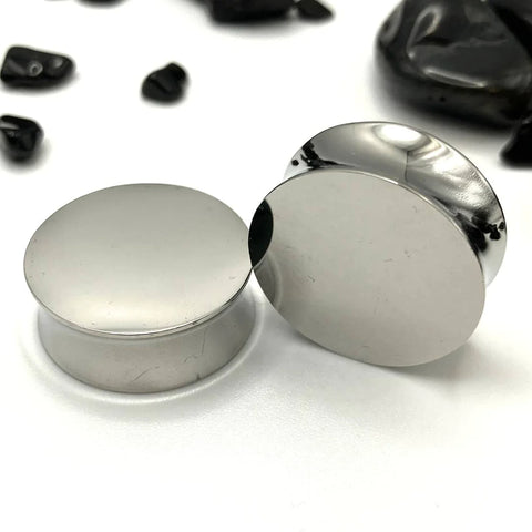 Shiny and polished solid steel ear plugs reflecting light.