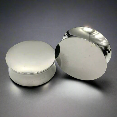 Shiny and polished solid steel ear plugs reflecting light.