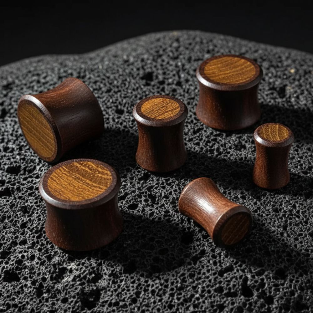 Sono Wood Plugs with Teak inlay on volcanic stone with dark, cinematic lighting.
