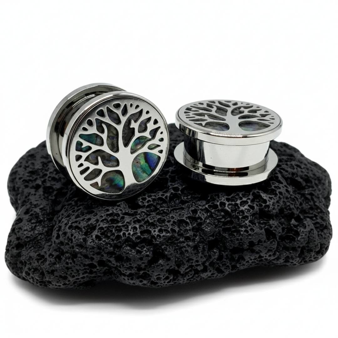 Pair of silver tree-of-life earrings on a black stone surface