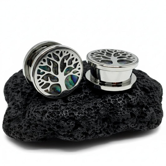 Pair of silver tree-of-life earrings on a black stone surface