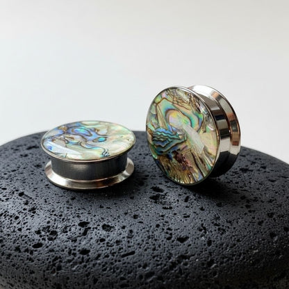 A pair of Steel Abalone Inlay Plugs on stone against a clean white studio backdrop.