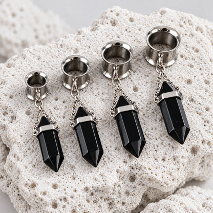 Close-up of the Steel Onyx Dangle Tunnels on volcanic stone against a clean white background.
