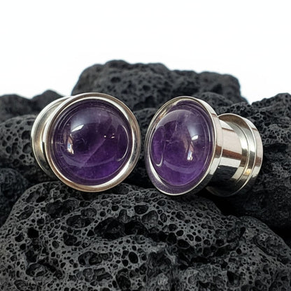 Steel Plugs Amethyst Inlay Gauges on Dark Volcanic Stone