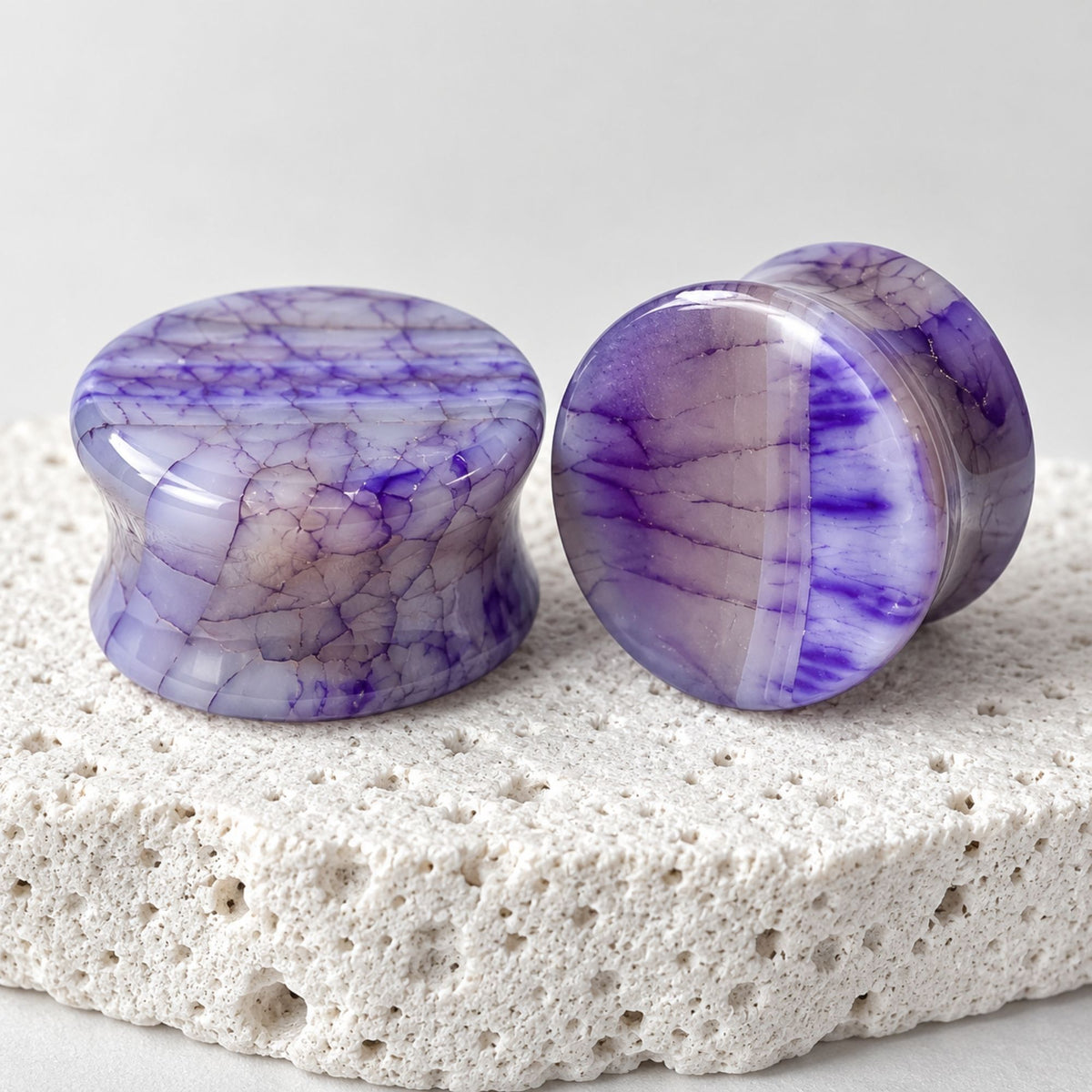 Purple Dragon Scale Agate Plugs (6mm-25mm) on stone against a bright white studio background.