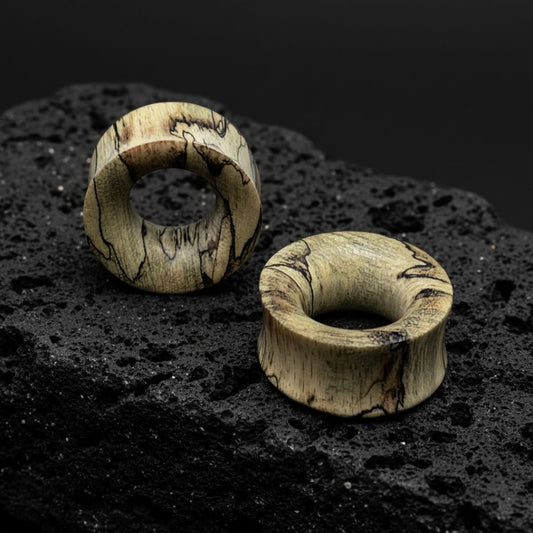 Close-up of dark brown Tamarind Wood Tunnels, displayed in varying sizes (2G to 1 inch) ideal for stretched ears.