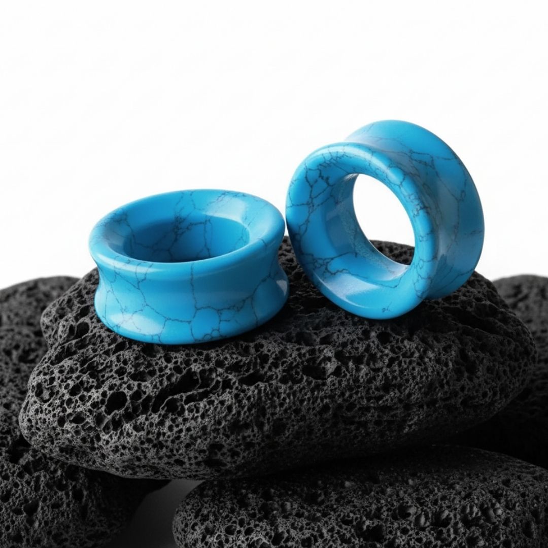 Pair of bright blue Turquoise stone tunnels (gauges) on a dark background. Organic double flare plugs for stretched ears.