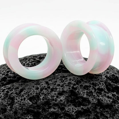 A pair of vibrant, swirled purple, pink, and blue unicorn silicone tunnels for stretched ears and alt fashion.