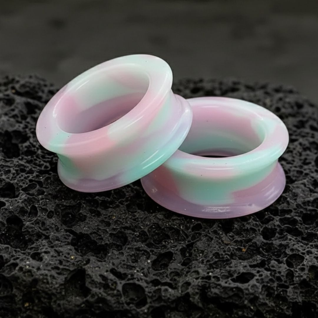 A pair of vibrant, swirled purple, pink, and blue unicorn silicone tunnels for stretched ears and alt fashion.