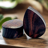 a pair of sono wood tear drop shaped plugs for stretched ears